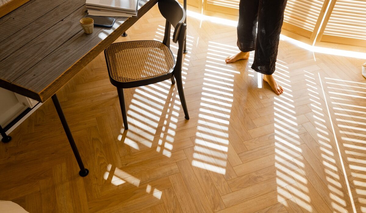 person standing on burnt orange herringbone flooring in a large home office
