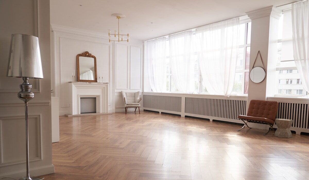 large interior with wood herringbone floors and natural light entering through the windows