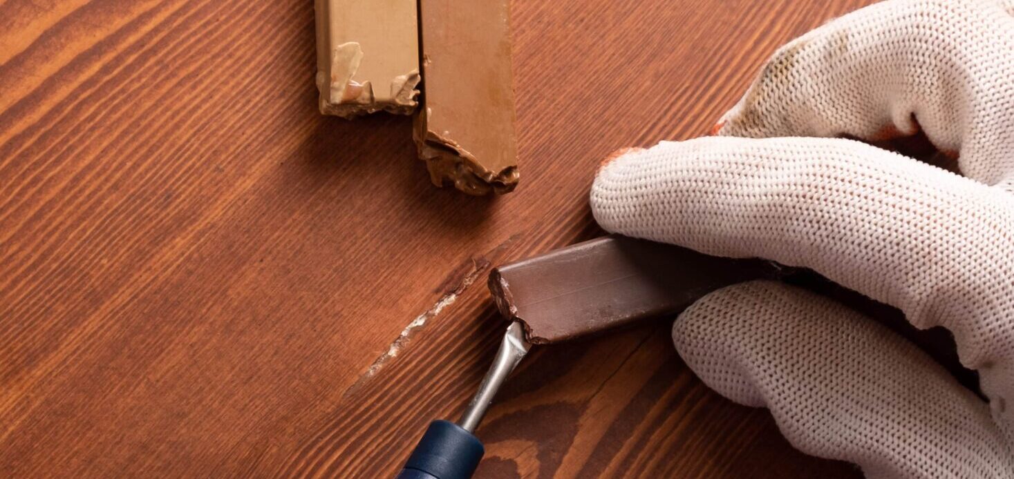 a hand restoring hardwood floor using a wax repair kit