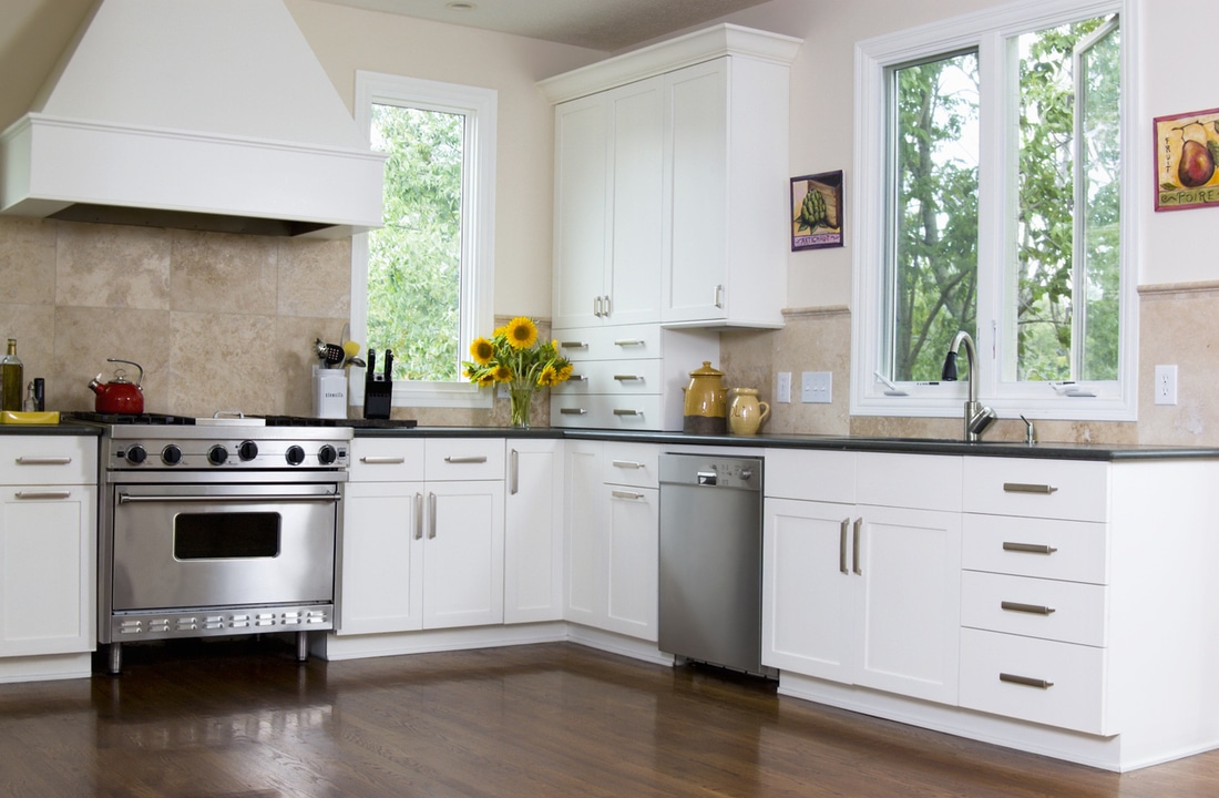 a kitchen with white cabinets and semi gloss wood floors