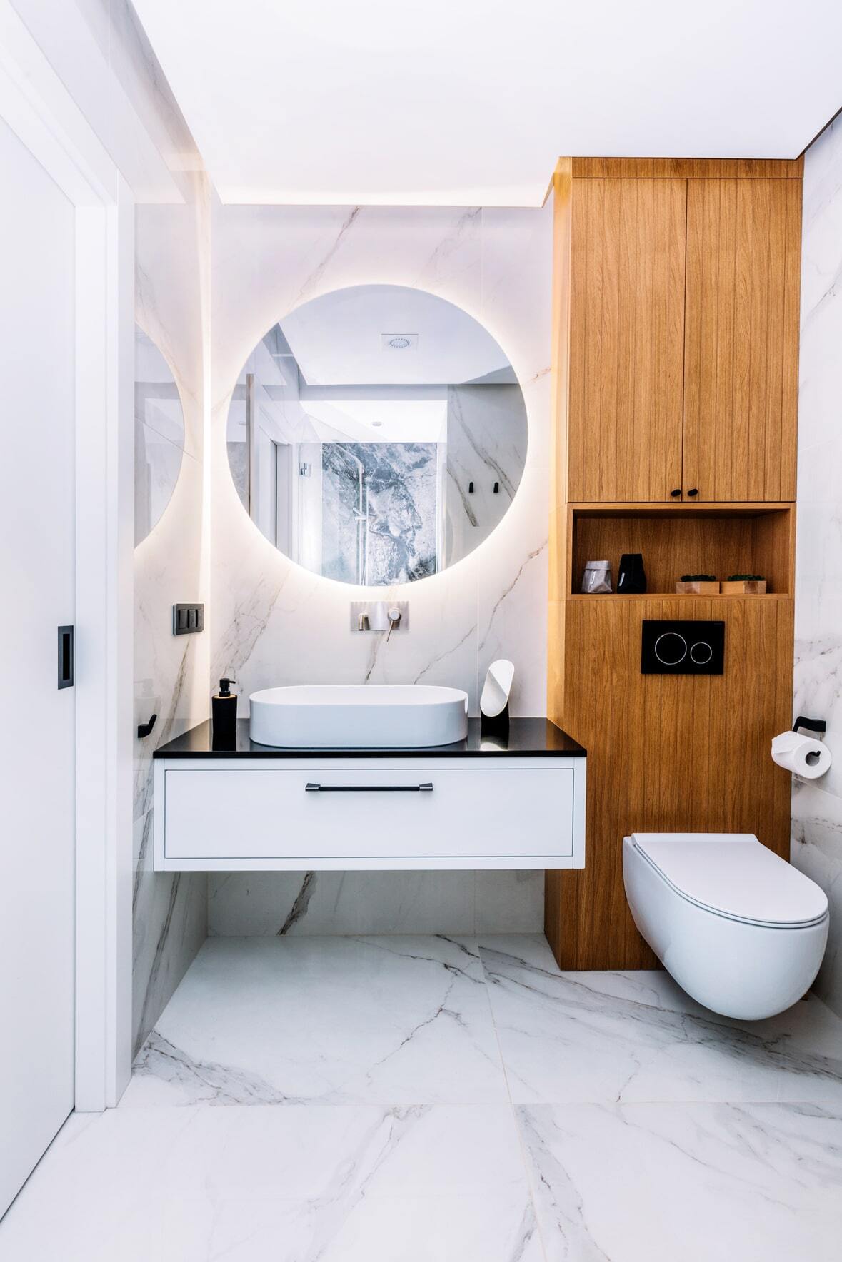 a small bathroom with white marble look vinyl tiles and wood wall paneling